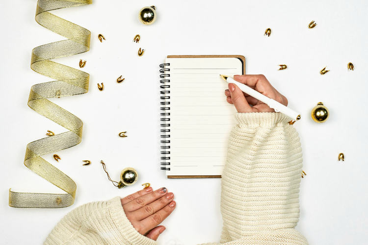 mulher escrevendo em um bloco de notas suas ideias de metas de ano novo
